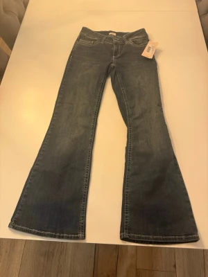  jeans från Nelly - Säljer ett par blå bootcut jeans från Nelly med snyggt broderade bakfickor i vitt. Har aldrig använt säljer då dom var förkort för mig som är 180. Stolek 38 💕