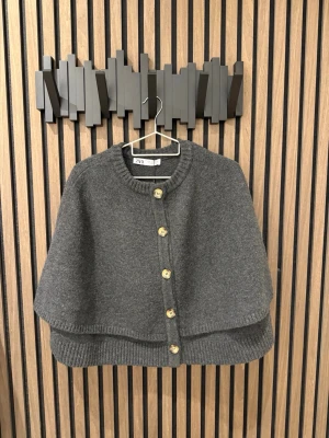 Poncho med knappar från Zara - Mörkgrå poncho med knappar från Zara, storlek M. Helt ny med prislapp kvar.  Aldrig använd.  Så fin och trendig. 