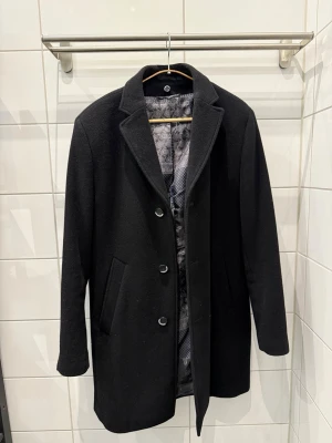 Svart Rock Herr - Svart rock herr  Sparsamt använd och i fint skick Avtagbar väst krage  Storlek: 48 Modern fit  Märke: Stones Material: 70% wool 20% polyamid 10% cashmere