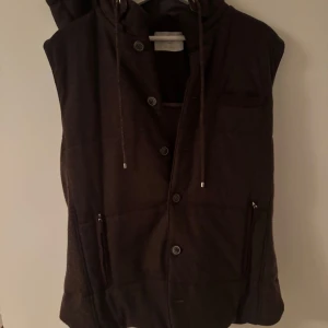 Brun väst från Gran Sasso - Snygg brun väst från Gran Sasso med knappar och dragkedja. Tillverkad i Italien med hög kvalitet och stilren design. Nypris 6000, säljer för 1900kr. Inga oseriösa bud.