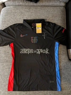 FC Barcelona x Nike Cactus Jack tröja S - FC Barcelona x Nike Cactus Jack limited edition matchtröja i svart med röda och blå detaljer på sidorna. Broderat FCB-märke, Nike-logga och Cactus Jack-tryck framtill. UNHCR-logga bak. Tillverkad i 100% polyester med Dri-FIT-teknologi.