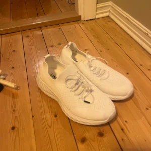 Vita sneakers med snörning - Säljer ett par fräscha vita sneakers från LINEAR med stickad ovandel och snörning. Skorna har en chunky platt sula och är perfekta för dig som gillar en clean och sportig look. Lätta och bekväma att bära till vardags.