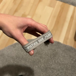 Grått Christian Dior armband - Ett helt nytt Dior armband i grå färg. Passar vem som helst då du kan spänna och lossa det hur du vill!