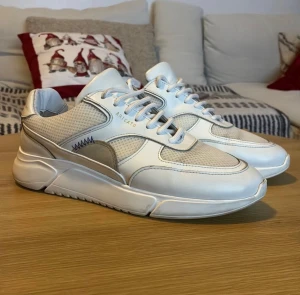 Axel Arigato Genesis - Snygga vita sneakers från Arigato. Perfekt för en avslappnad men stilfull look. Nypris 2700:-  Använda men i fortsatt bra skick. I storlek 40. Finns en liten reva på vänster tåkappa som är cirka 1cm men påverkar ej skicket eller syns direkt. 