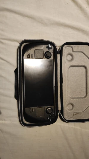 Valve Steam Deck - Valve Steam Deck i originalfodral. Handhållen PC-spelkonsol med stor skärm, styrspakar och knappar. Skärmen och chassit ser ut att vara i gott skick utan synliga repor eller skador. Perfekt för gaming på språng. Fodralet ingår.