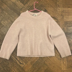 Ljusrosa stickad tröja från Gina Tricot - Supermysig ljusrosa stickad tröja från Gina Tricot med rund hals och ribbade muddar vid ärmslut och nederkant. Använd några enstaka gånger men har blivit lite nopprig på ärmarna