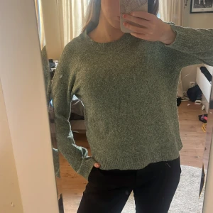 Grön stickad tröja - Mysig grön stickad tröja från Vero Moda i storlek S. Tröjan har rund hals, ribbade muddar och långärmad passform. Perfekt för dig som gillar enkel och chill stil med lite loose fit. Materialet är mjukt och skönt, passar till jeans eller svarta byxor.