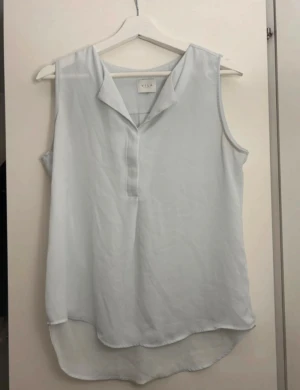 Ljusblå blus Vila - Ärmlös blus från Vila, storlek S. Ganska genomskinligt tyg och lite längre där bak