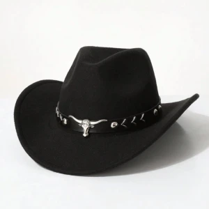 Svart cowboyhatt med horn-detalj - Cool svart cowboyhatt med bred brätte och dekorerat band i svart läderlook. Bandet har silvriga detaljer och en metallskalle med horn framtill. Perfekt för dig som vill sticka ut med westernstil.