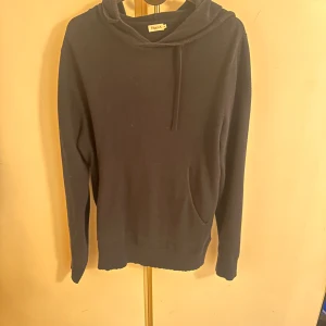 Stickad hoodie från Filippa K  - Mörkblå hoodie från Filippa K i storlek XS. Tröjan har huva med snörning, en klassisk känguruficka framtill och långa ärmar. Materialet känns mjukt och skönt, perfekt för chill dagar. Enkel och stilren design som funkar till det mesta. Köpt för 1999kr, säljer för endast 449kr 