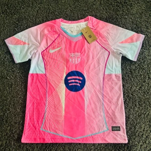 Barcelona rosa special edition 25/26 - Tröjan är helt ny och i toppskick, gjord i ventilerande polyester som är perfekt både för match och träning, tröjan är rosa och blå och har spotify loggan på magen som sponsor i mörkblå färg, tröjan är helt ny, en replika
