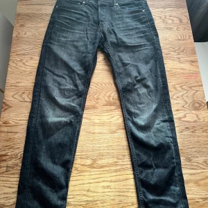 Mörkblå jeans från Jack & Jones - Snygga mörkblå jeans från Jack & Jones med klassisk femficksdesign och läderpatch bak i midjan. Jeansen har en rak passform och är tillverkade i slitstarkt denimtyg. Perfekta för dig som gillar en enkel och stilren look.