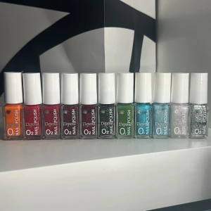 Depend nagellack - Säljer ett set med 10 Depend O2 nagellack i olika färger: orange, röd, vinröd, mörklila, svart med glitter, grön, blå, ljusblå, silver och glitter. Små flaskor med 5 ml i varje