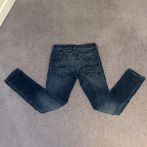 Slim Glenn mörkblå jeans 27/30 - Mörkblå jeans från Jack & Jones i slim fit-modell. Dessa par sitter riktigt bra för sig som vill ha lite tajtare jeans men som också är stretchig. Perfekt för dig som gillar att använda jeans i vardagen.