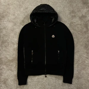 Moncler Backpadded Cardigan - ‼️INGA BYTEN‼️Svart Moncler Backpadded Cardigan - storlek = L (fits M) - skick: 9,5/10 en onsynlig lagning innanför luvan - håller värmen otroligt bra, man kan ha den som en vinterjacka om man har en merinoull tröja under - pris: 6000kr - oseriösa och sånna som inte har pengarna redo behöver inte skriva - Fråga gärna om bilder eller annat vid intresse av köp! Mvh 