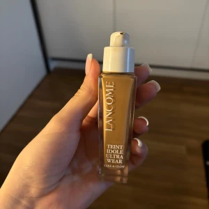 Lancome Teint Idole Ultra Wear foundation - Lancome Teint Idole Ultra Wear Care & Glow foundation i en snygg glasflaska med vit pump och lock. Färgen är varm beige/brun med glow-finish, perfekt för en fräsch och jämn hudton. Enkel att applicera och ger ett naturligt resultat. Använt fåtal gånger