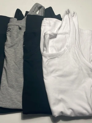 4-pack baslinnen  - Säljer ett 4-pack med klassiska baslinnen. Ett linne är vitt, två är svart och ett är gråmelerat. Alla har rund halsringning och är ärmlösa, perfekta att bära till jeans eller shorts. Superenkla att matcha och sköna mot huden.