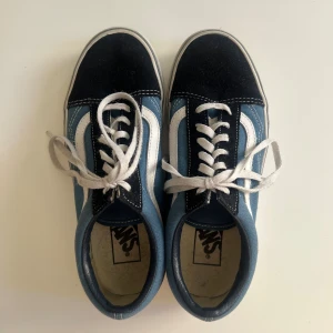 Vans Old Skool blå/svarta sneakers - Klassiska Vans Old Skool sneakers i blått och svart med vit sula och vit sidosnirk. Skorna är använda fåtal gånger (5 ggr) och är i mycket fint skick!!! Köpta för 699kr i våras.🤍