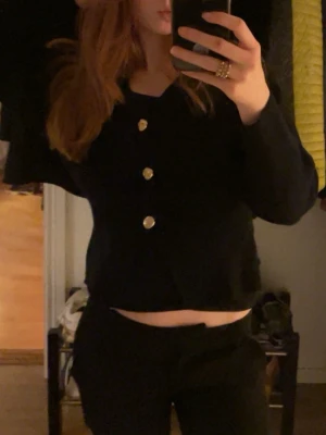 Svart kofta med guldknappar Gina Tricot - Säljer en svart kofta från Gina Tricot i storlek XS. Koftan har v-ringning, långa ärmar och tre stora guldknappar framtill. Materialet känns skönt och stretchigt. Knappen längst ned har åkt av men har sytt tillbaka den. Använd fåtal gånger. Säg till för mer bilder💗💗