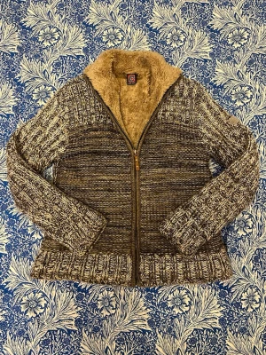 Kofta - Cardigan med värmande fodring. Grovstickad utsida i kombination med innerfoder. På etiketten står storlek M, men den sitter som s/xs. Inga defekter