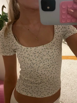 Blommig vit topp med  ringning - Säljer en söt vit topp med små blå blommor. Jättebra skick! Knappt använd! Storlek xs