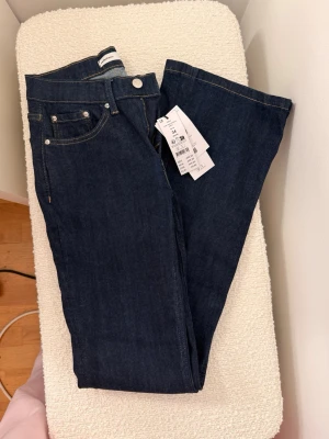 Bootcut jeans i mörkblå denim - Snygga bootcut jeans från Perfect Jeans i mörkblå denim. Modellen har låg midja och klassisk femficksdesign med kontrastsömmar. Materialet är slitstarkt jeans och passformen är loose med bootcut-ben. Perfekt för dig som gillar retrovibbar och vill ha en cool siluett.