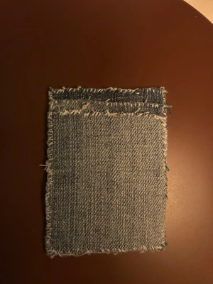 Blå jeansplånbok med fransig kant - Unik plånbok gjord av blått jeansmaterial med fransiga kanter för en cool och avslappnad vibe. Plånboken har en sugpropp på baksidan som gör att den lätt kan fästas på släta ytor som din mobiltelefon. Perfekt för dig som är trött på att tappa bort kortet !