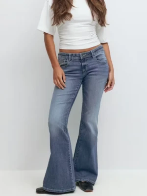 Blå bootcut jeans med låg midja - Säljer ett par snygga blå bootcut jeans med låg midja med rosa tryck på fickorna.  De är helt oanvända men säljer då de inte kommit till användning ! 🥰