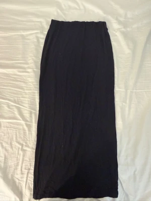 Svart långkjol från 157, storlek XS - Säljer en svart långkjol från 157 i storlek XS. Kjolen har en enkel och rak design med resår i midjan för skön passform. Perfekt att styla med sneakers eller boots. Materialet känns mjukt och lätt, vilket gör den bekväm att bära hela dagen.