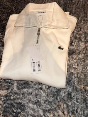 Vit half zip tröja från Lacoste - Quarter Zip från Lacoste. Helt Ny aldrig andvänd Finns även i grå Om ni köper fler än 1 får ni rabbat 💯. Fast pris finns inte 