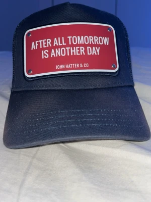 John hatter keps - Säljer en mörkblå John Hatter keps med en text som står ”After All Tomorrow Is Another Day. Den är lite lite solblekt på skärmen men den är typ som nu. Har du några frågor eller funderingar så är de bara att skriva. Pris går att diskutera.