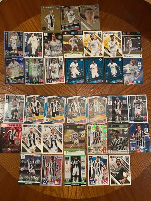 Samling fotbollskort Juventus & Real Madrid - Stor samling fotbollskort med spelare från Juventus och Real Madrid. Korten har olika designer, färger och holografiska effekter. Flera kända spelare i svartvita och vita matchställ. Perfekt för samlare eller fotbollsälskare som vill utöka sin kollektion.