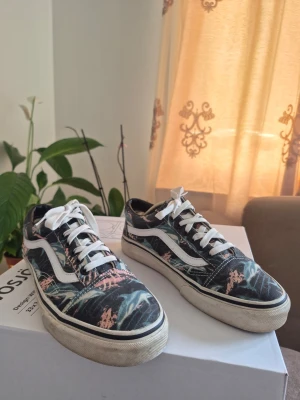 Vans Old Skool sneakers med en delfinmönstrad EUR 40 - Snygga Vans sneakers med lågt skaft och tropiskt delfinmönster i blått, rosa och grönt. Skorna har vit sula, klassisk vit sidestripe och vita skosnören. Perfekta för dig som vill sticka ut med en unik stil.