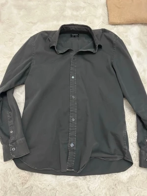 Grå skjorta från Dondup Regular Fit - Snygg grå skjorta från Dondup i regular fit. Skjortan har klassisk krage, långa ärmar och knäppning framtill. Perfekt för dig som gillar en stilren och enkel look. Tillverkad i mjukt bomullstyg.