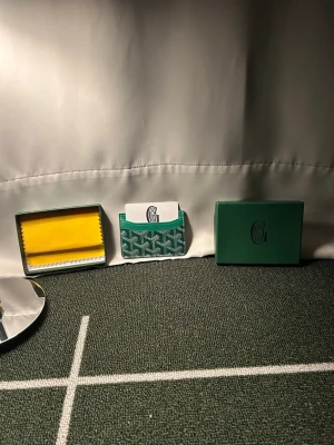 Grön korthållare  - Snygg grön korthållare från gy i klassiskt mönstrat läder. Kommer med originalask och putsduk. Perfekt för kort och ID, smidig att ha i fickan. Ikonisk design med Gy logga och vita detaljer.