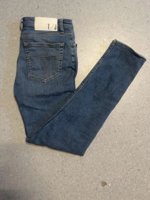 Tiger of sweden jeans - Säljer ett par klassiska blå slim jeans från T/J. Jeansen har en bakficka med kontrastsömmar och är tillverkade i ett stretchigt denimtyg som sitter tight hela vägen ner. Perfekta till en avslappnad look och funkar året runt. 29/30. 