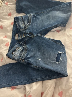 Ltb Jeans - Ett par blå jeans från LTB med slitningar och ett hål på ena benet. Jeansen har klassisk femficksmodell, dragkedja och knapp i midjan samt bälteshällor. Materialet är denim i bomull med en tvättad look och ljusa detaljer. Passar mig bra i längden som e 165💕