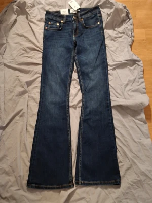 jeans  - Snygga bootcut jeans i mörkblå tvätt med låg midja och kort längd. Klassisk femficksdesign och kontrastsömmar. Perfekta för dig som gillar en retro vibe och vill ha ett par jeans som sitter tajt upptill och släpper vid benen.
