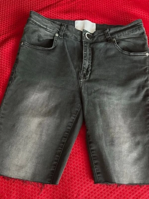 Svarta jeansshorts St. 29 ( M)  - Snygga svarta jeansshortsoch knappstängning i midjan. Shortsen har en lätt tvättad look och bälteshällor, perfekta för en avslappnad stil.