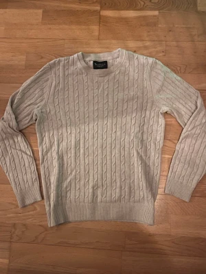 Beige kabelstickad tröja Bondelid - Kabelstickad beige tröja från Bondelid i storlek S. Klassisk och stilren design, perfekt för lager-på-lager. Mjukt material som känns skönt mot huden.