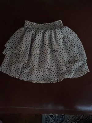 Söt beige prickig kjol, storlek 134/140🌟🌟❤️🩷🩷🤩 - Supersöt kort kjol i beige med svarta prickar och flera lager volanger. Kjolen har en bred, smockad midja som ger en bekväm passform och ett luftigt, flowy material som känns lätt på sommaren.🤩🤩🩷🩷🩷