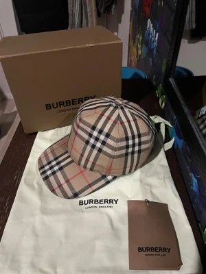 ÄKTA!! Burberry keps - Säljer min Burberry keps då den är för liten på mig och ej kommer till nån användning. OBS! ÄKTA! Låda, dustbag samt prislapp kommer med, ska se vart kvittot är men kan bli svårt att hitta då kepsen är köpt för 3 år sedan. Den har inga skador eller så och är sparsamt använd. Byten går även bra😊 Om du är intresserad eller har frågor så är det bara att höra av dig🤝