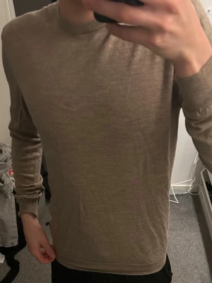 Beige merinoulltröja från Matinique nypris 1200  - Säljer en stilren beige stickad tröja från Matinique i 100% merinoull. Tröjan har rund halsringning, långa ärmar och ribbade muddar vid ärmslut och nederkant. Perfekt för dig som gillar klassisk och enkel stil.