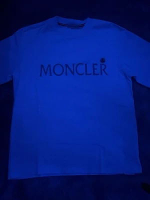 Vit Moncler t-shirt med logga - Snygg vit t-shirt från Moncler med stor logga tryckt över bröstet och ett litet Moncler-märke på ärmen. Klassisk rund halsringning och korta ärmar. Tillverkad i mjuk bomull för en skön känsla och clean look. Är Xs men passar även s 🤩⛱️