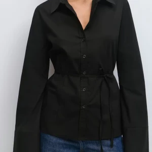 Svart skjorta med knyt i midjan - Svart shaping skjorta med knyte i midjan. Har även lite vidare ärmar vilket är supersnygg detalj!💚 går att knyta både i ryggen, på framsidan eller i sidan, beroende på vad man önskar. Använd 1 gång.🤌🏻