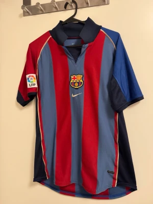 Barcelona matchtröja Nike - Säljer en klassisk FC Barcelona matchtröja från Nike i storlek XL kids or S men . Tröjan har breda röda och blå ränder, klubbmärke på bröstet, LFP-märke på ärmen och Dri-FIT-material som andas. Perfekt för dig som älskar fotboll och vill ha en ikonisk look.