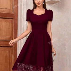 Vinröd klänning med spets från Miusol - Vinröd klänning med hjärtformad urringning, korta puffärmar och vidd i kjolen. Nederdelen har en snygg spetsdetalj som ger extra stilpoäng. Perfekt för dig som vill sticka ut med en elegant look.