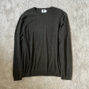 Mörkgrön stickad tröja från NN07 - Snygg mörkgrön 100% ullstickad tröja från NN07 i klassisk modell med rund halsringning och ribbade muddar. Perfekt för lager-på-lager och enkel att matcha med jeans eller chinos. Materialet är mjukt och tunt, vilket gör den skön att bära hela dagen. Materialet är 100% ull i storlek L men den sitter mer som en Medium. Tröjan är nästan ny, endast använd fåtal gånger! Skriv vid minsta intresse! Mvh DC 🔹