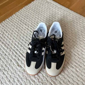 Adidas Samba OG svart/vit sneakers - Adidas Samba OG sneakers i svart och vitt med klassiska tre ränder på sidan och gummisula. Ovandel i mocka och skinn, snörning framtill och rund tå. Helt oanvända med prislapp kvar. Finns ett par vita skosnören till också. Nypris 1449💗