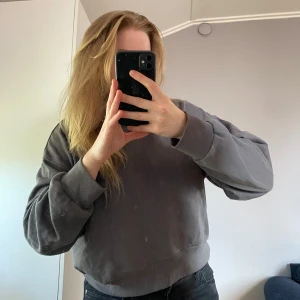 Grå oversized sweatshirt - Enkel och stilren grå sweatshirt med oversized passform och breda muddar vid ärmslut och midja. Perfekt för en avslappnad look och passar till det mesta. Mjuk och skön, med lång ärm och rund hals.